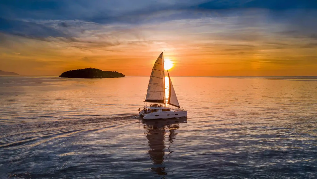 Sailing catamaran under way at sunset in Komodo National Park