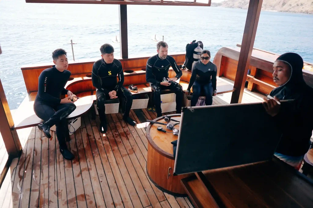 Guests in wetsuits on the dive deck of a charter boat